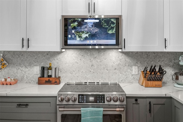 kitchen with gray cabinets, white cabinetry, backsplash, stainless steel appliances, and light stone countertops