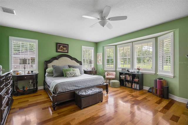 bedroom with a textured ceiling, ceiling fan, and hardwood / wood-style floors