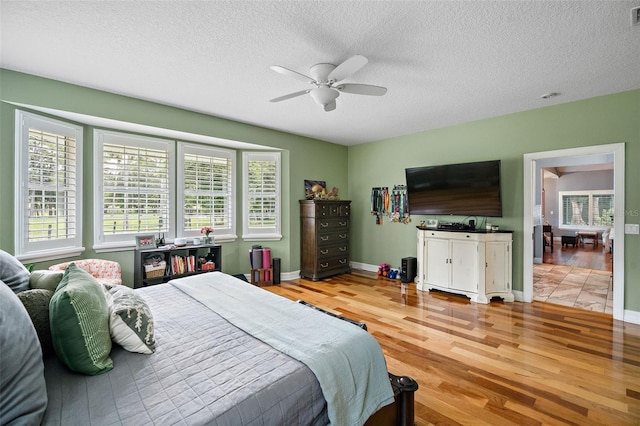 bedroom with a textured ceiling, ceiling fan, and light wood-type flooring