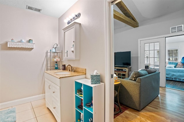 bathroom featuring a textured ceiling, vanity, beamed ceiling, and wood-type flooring