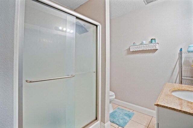 bathroom with an enclosed shower, vanity, toilet, and a textured ceiling