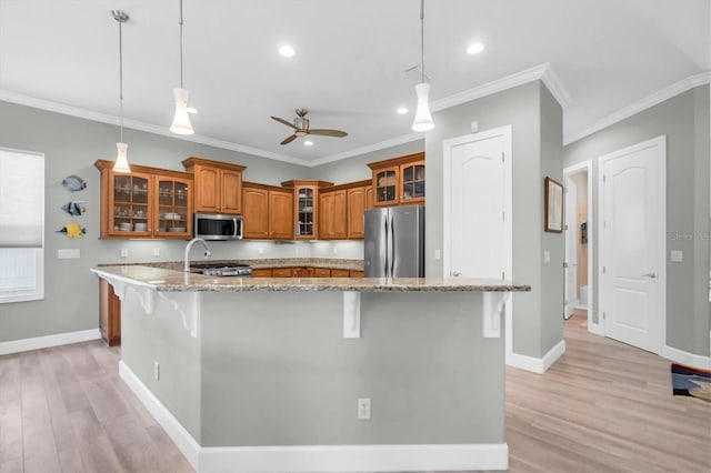 kitchen featuring stainless steel appliances, baseboards, brown cabinets, and a kitchen breakfast bar