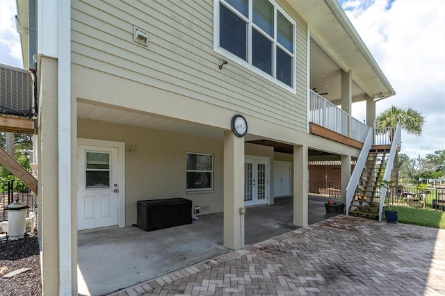 rear view of property featuring a patio, french doors, stairway, and stucco siding