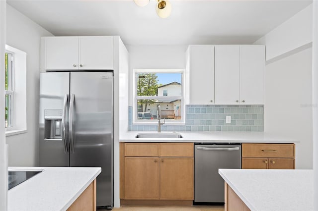 kitchen featuring white cabinets, appliances with stainless steel finishes, decorative backsplash, and sink