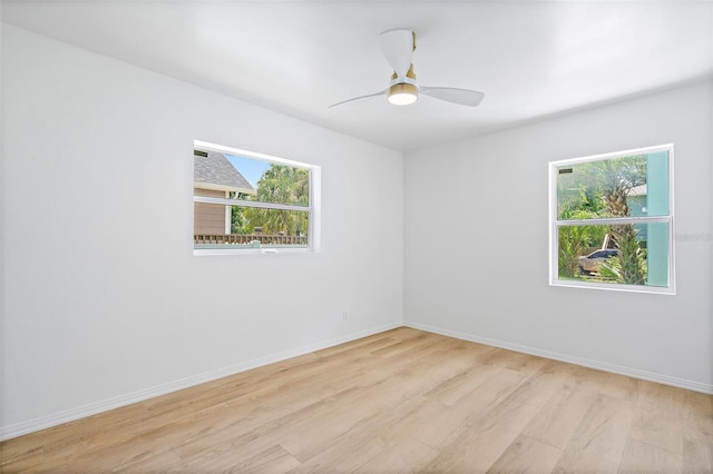 empty room with ceiling fan, plenty of natural light, and light hardwood / wood-style flooring