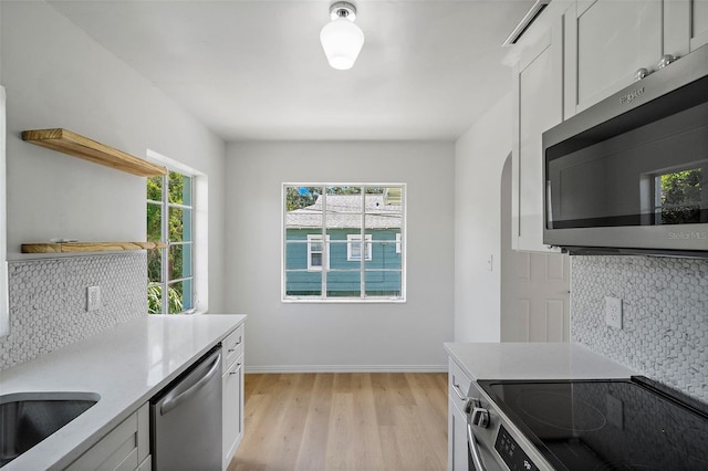 kitchen featuring light hardwood / wood-style flooring, stainless steel appliances, sink, decorative backsplash, and white cabinets