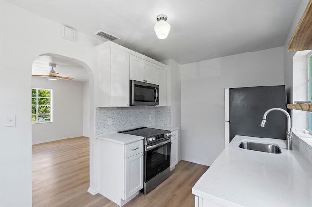 kitchen with white cabinets, appliances with stainless steel finishes, sink, and ceiling fan