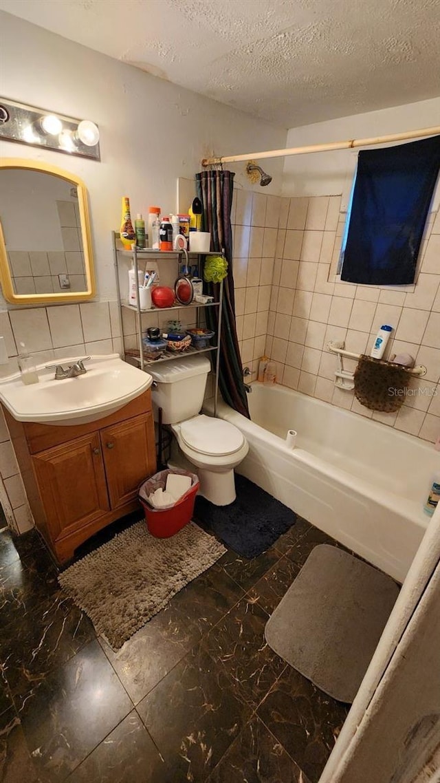 bathroom with shower / tub combo, a textured ceiling, tile walls, and vanity