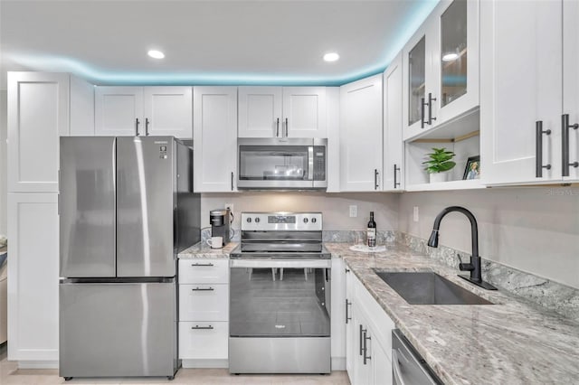 kitchen featuring light stone counters, stainless steel appliances, white cabinetry, and sink