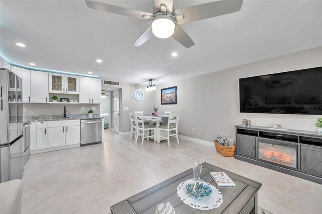 tiled living room featuring ceiling fan and sink