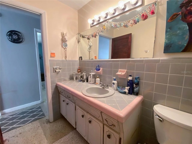 bathroom featuring vanity, toilet, tile walls, and tasteful backsplash