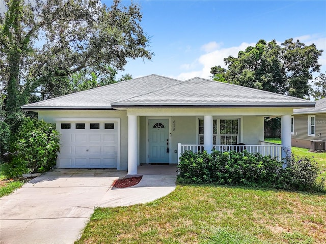 view of front of property featuring a garage, a front lawn, covered porch, and central AC