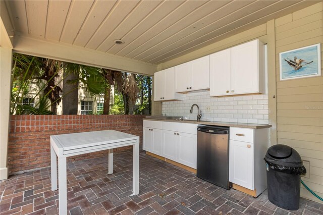 kitchen with white cabinetry, dishwasher, and wooden walls