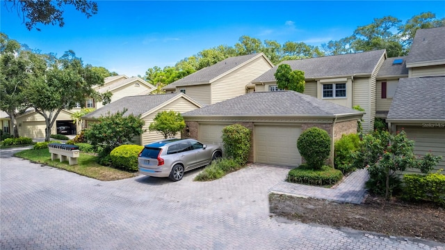 view of front of house featuring decorative driveway, a garage, and roof with shingles