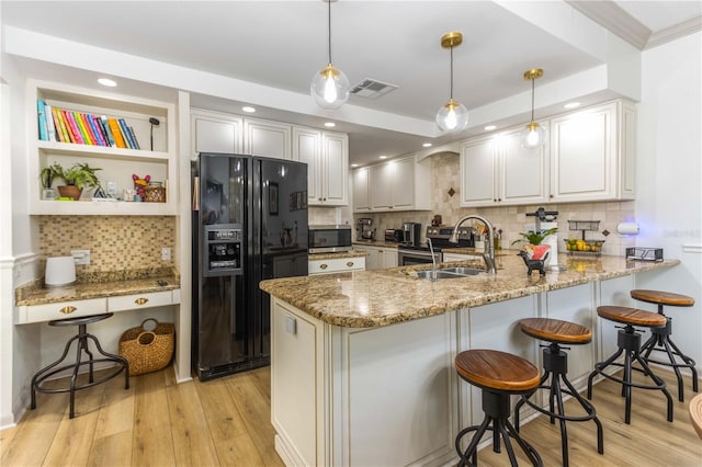 kitchen with kitchen peninsula, light stone countertops, hanging light fixtures, and black fridge with ice dispenser