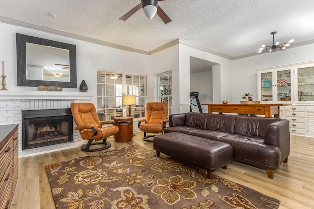 living room featuring a textured ceiling, ornamental molding, a brick fireplace, and hardwood / wood-style floors