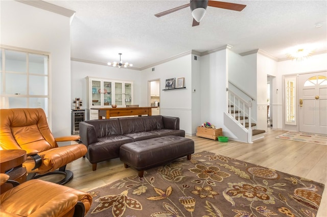 living room featuring light hardwood / wood-style floors, crown molding, a textured ceiling, and ceiling fan with notable chandelier