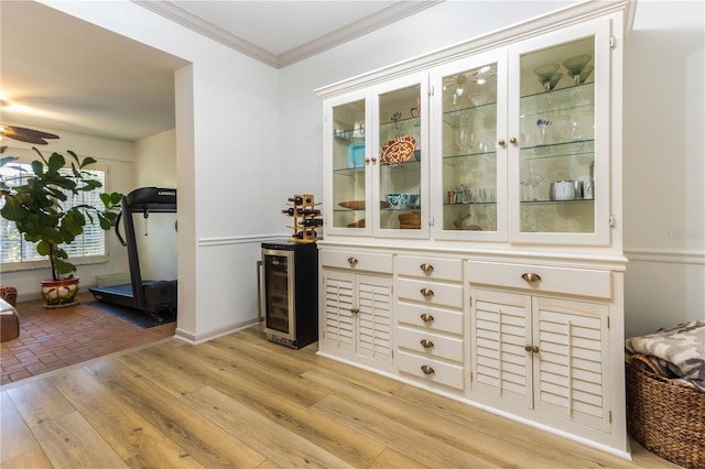 bar with wine cooler, ornamental molding, light wood-type flooring, white cabinets, and ceiling fan