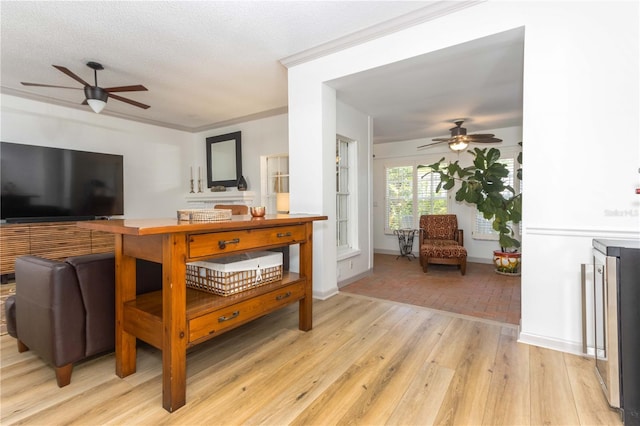 living room featuring crown molding, light wood-type flooring, beverage cooler, a textured ceiling, and ceiling fan