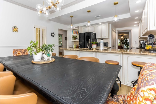 dining room with light hardwood / wood-style flooring, ornamental molding, sink, a raised ceiling, and a chandelier