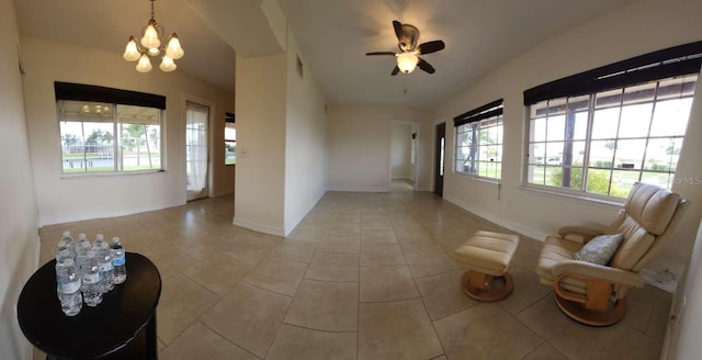 unfurnished living room with ceiling fan with notable chandelier and light tile patterned flooring