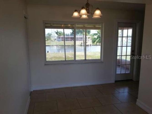 unfurnished dining area with dark tile patterned flooring and a notable chandelier