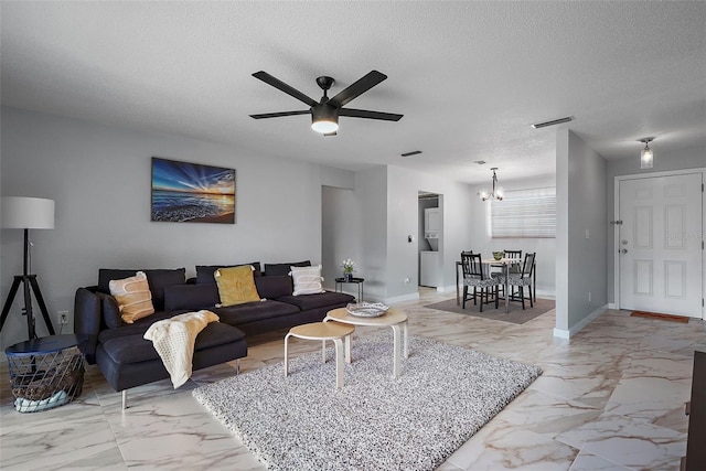 living room with ceiling fan with notable chandelier and a textured ceiling