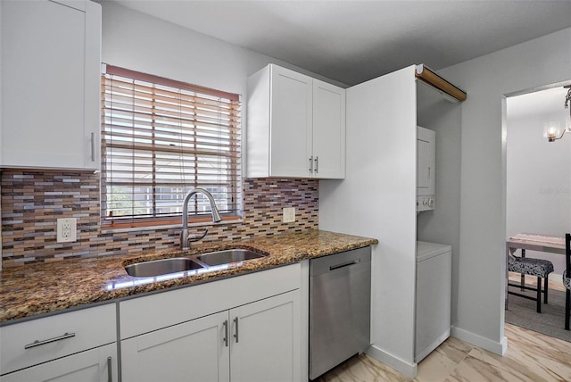 kitchen featuring dark stone countertops, stainless steel dishwasher, sink, and white cabinets