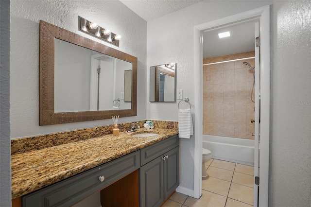 full bathroom with a textured ceiling, vanity, toilet, tiled shower / bath, and tile patterned floors