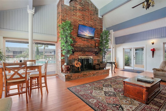 living room with a healthy amount of sunlight, high vaulted ceiling, wood-type flooring, and a fireplace