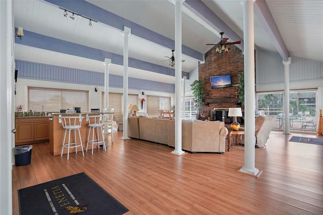 living room with light hardwood / wood-style flooring, ceiling fan, beamed ceiling, and ornate columns