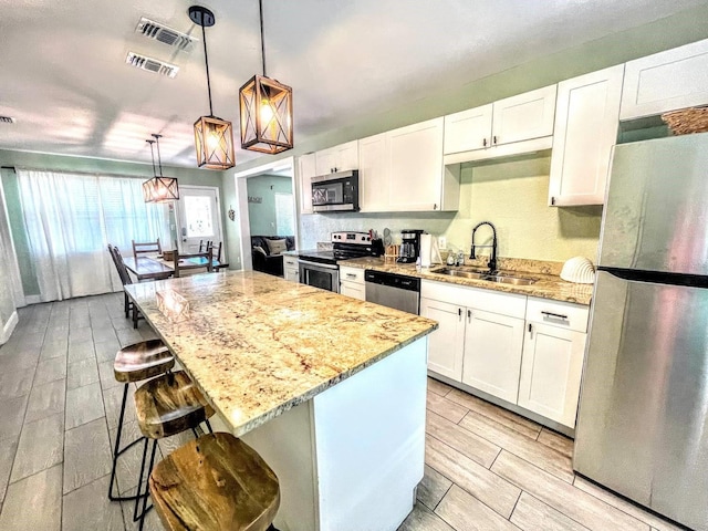 kitchen featuring a kitchen bar, a kitchen island, stainless steel appliances, and white cabinets