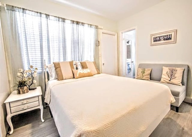 bedroom with multiple windows and dark hardwood / wood-style floors