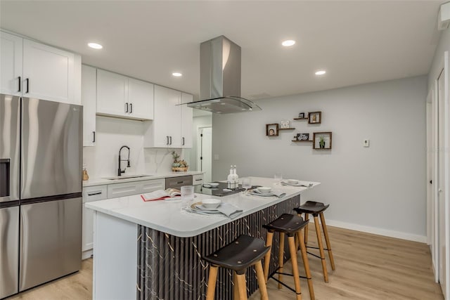 kitchen with light hardwood / wood-style flooring, appliances with stainless steel finishes, sink, island exhaust hood, and a kitchen breakfast bar