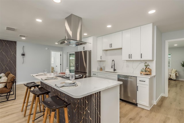 kitchen with a center island, stainless steel appliances, light hardwood / wood-style floors, island exhaust hood, and a kitchen breakfast bar