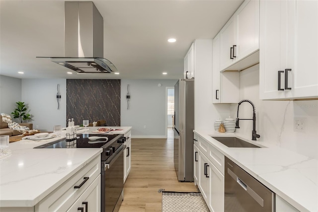 kitchen with light stone countertops, light hardwood / wood-style flooring, appliances with stainless steel finishes, island exhaust hood, and sink