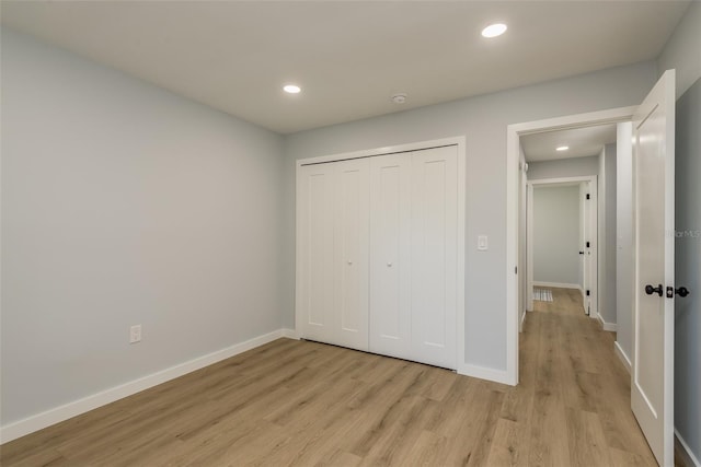 unfurnished bedroom featuring light wood-type flooring and a closet