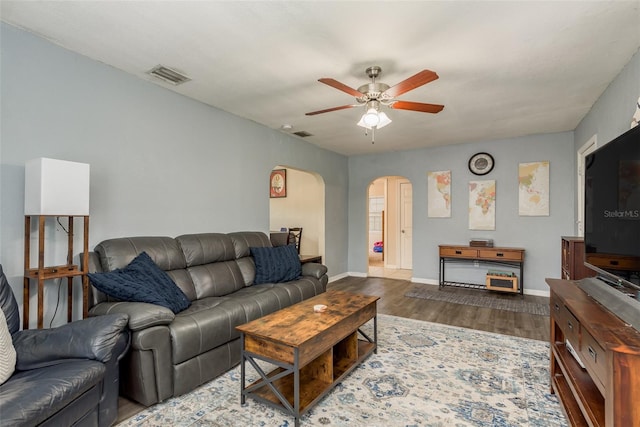 living room featuring dark wood-type flooring and ceiling fan