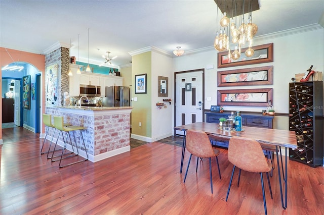 dining area with beverage cooler, ornamental molding, hardwood / wood-style floors, and a notable chandelier