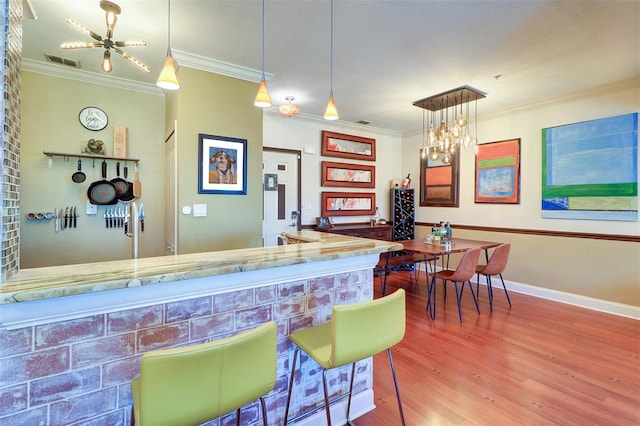 bar featuring hanging light fixtures, hardwood / wood-style flooring, a chandelier, and ornamental molding