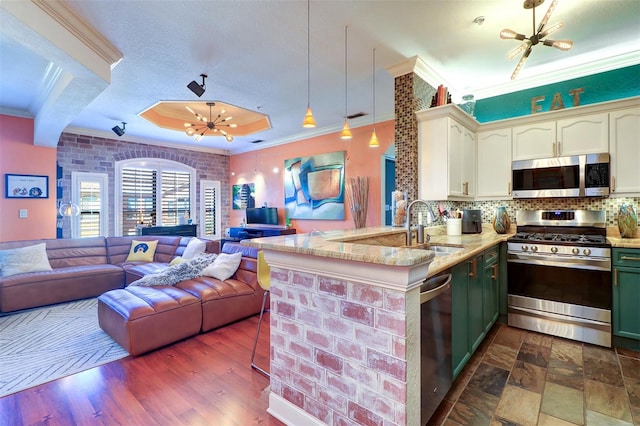 kitchen with an inviting chandelier, decorative light fixtures, stainless steel appliances, sink, and kitchen peninsula