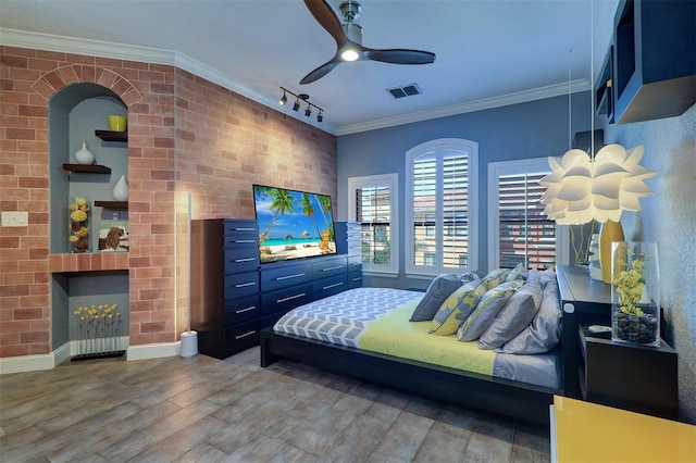 bedroom featuring rail lighting, ceiling fan, hardwood / wood-style flooring, and crown molding