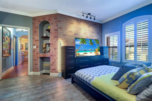 bedroom featuring a textured ceiling, wood-type flooring, a large fireplace, ornamental molding, and track lighting