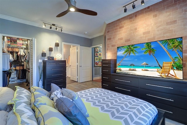 bedroom featuring crown molding, light hardwood / wood-style flooring, track lighting, a closet, and ceiling fan