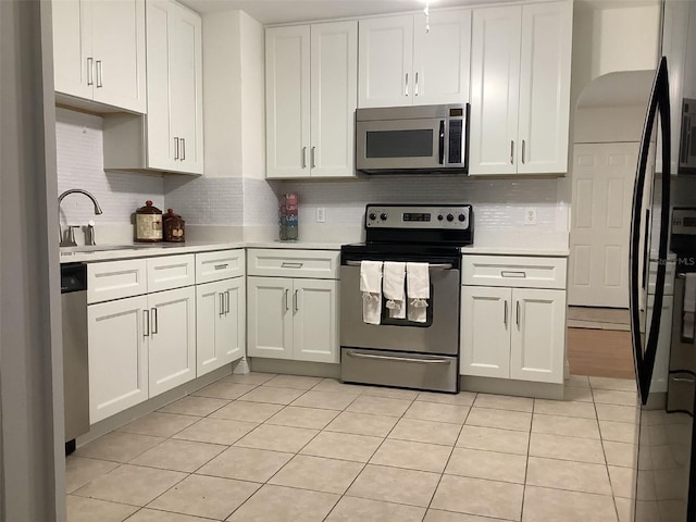 kitchen featuring white cabinets, light tile patterned floors, stainless steel appliances, and decorative backsplash