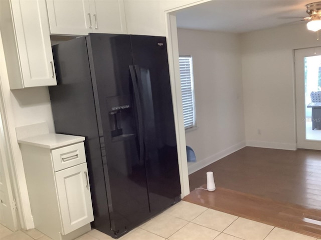 kitchen with black refrigerator with ice dispenser, white cabinetry, ceiling fan, and light hardwood / wood-style floors