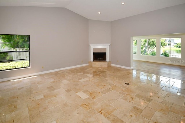 unfurnished living room featuring light wood-type flooring, high vaulted ceiling, and plenty of natural light