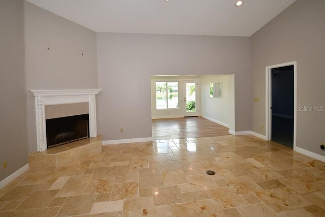 unfurnished living room with high vaulted ceiling and a fireplace