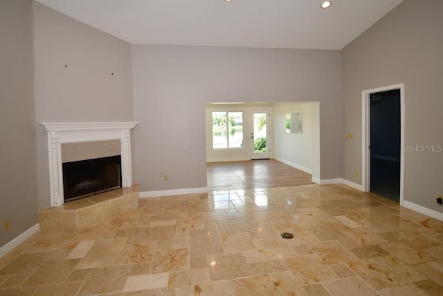 unfurnished living room with baseboards, a tile fireplace, recessed lighting, and stone tile floors