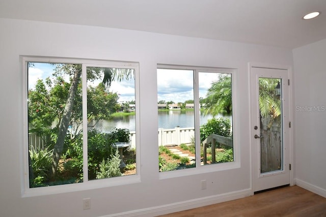 doorway featuring baseboards, wood finished floors, a water view, and recessed lighting